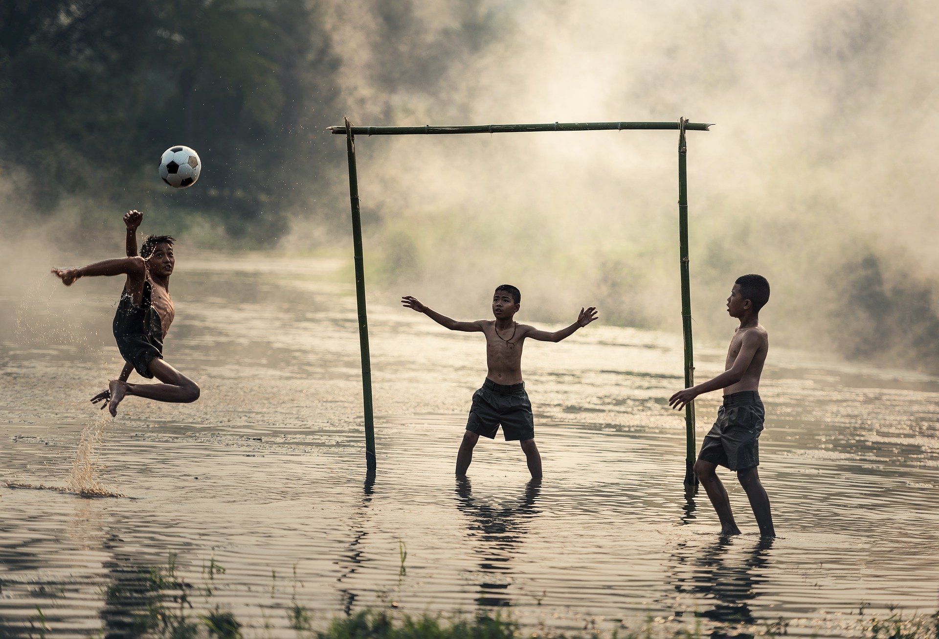 Children playing soccer in water